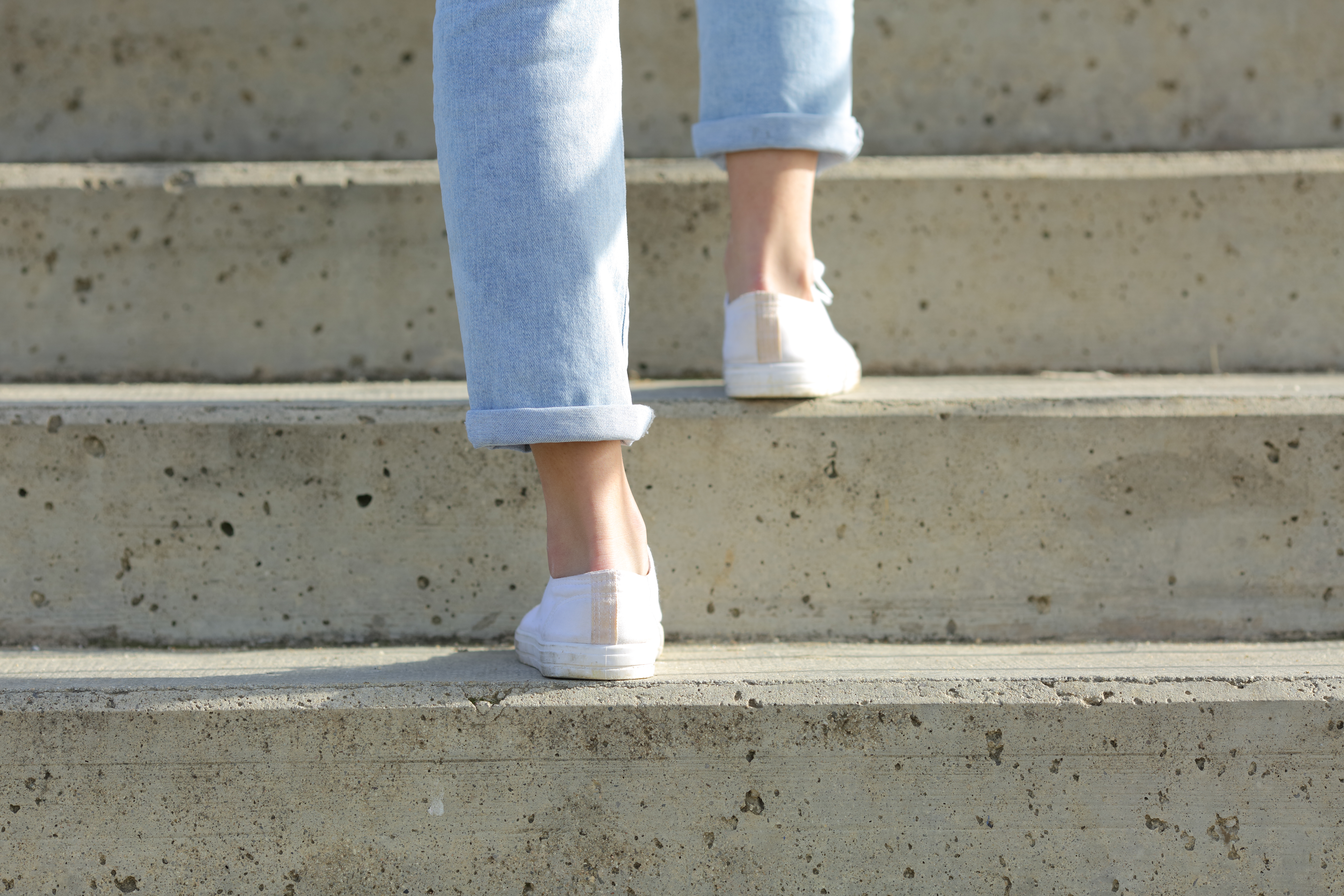 Back view close up of a woman legs wearing sneakers walking up stairs