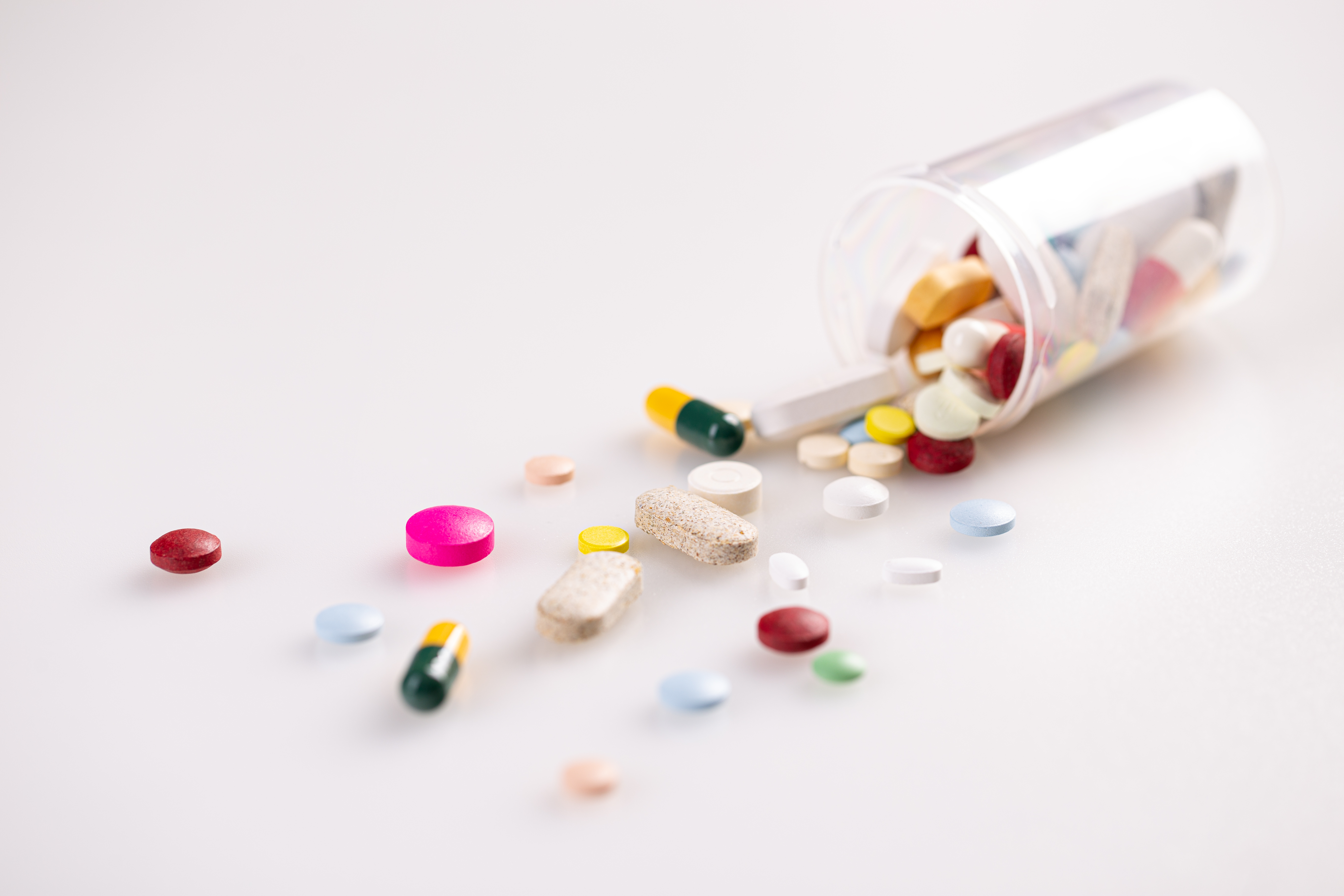 Bottle with different pills on white background