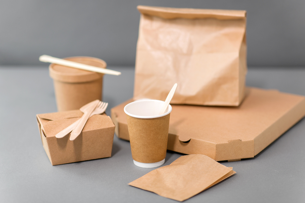 package, recycling and eating concept - disposable paper containers for takeaway food on table